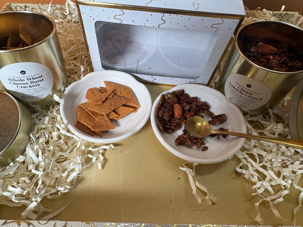Open Diwali gift box with gold tins of crackers and granola, plated servings and a gold spoon in front