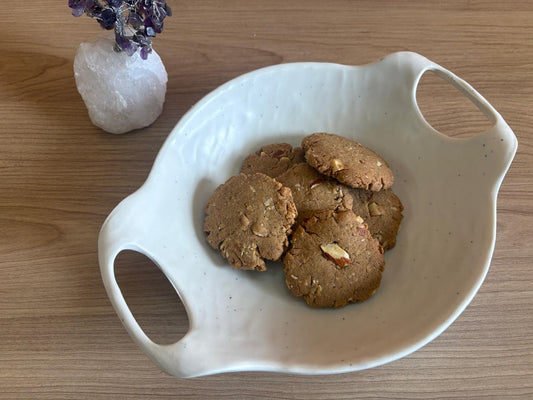 Jowar almond cookies with whole almond pieces in a white ceramic bowl on a wooden table, no maida, Fluffiesta Gurgaon