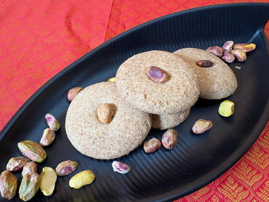 Close-up of jowar nankhatai cookies with pistachio and almond on a black tray
