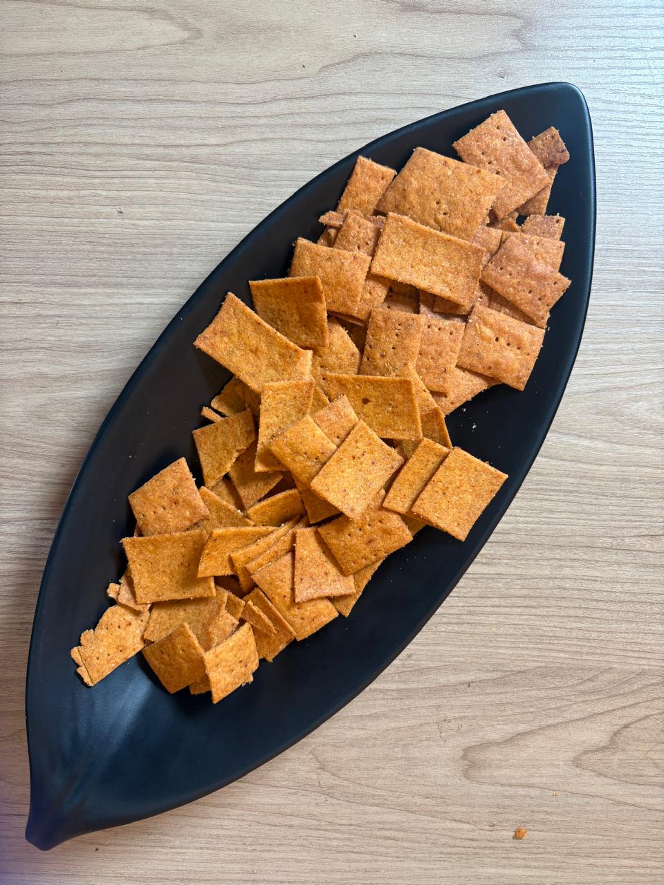 Peri peri whole wheat crackers piled on a black leaf-shaped plate, Fluffiesta Gurgaon