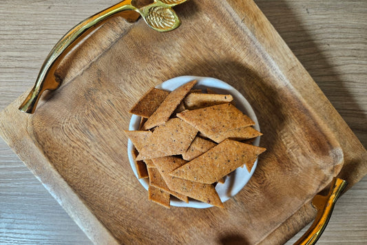 Whole wheat cheese crackers from Fluffiesta Gurgaon in a white bowl on a wooden serving tray with gold leaf handles