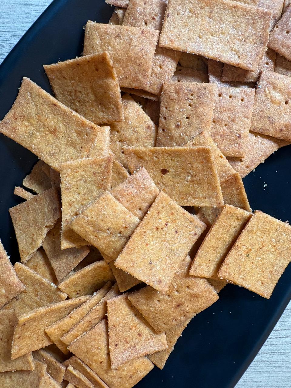 Close-up of crisp square peri peri whole wheat crackers with docking holes, Fluffiesta Gurgaon