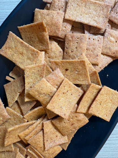 Close-up of crisp square peri peri whole wheat crackers with docking holes, Fluffiesta Gurgaon