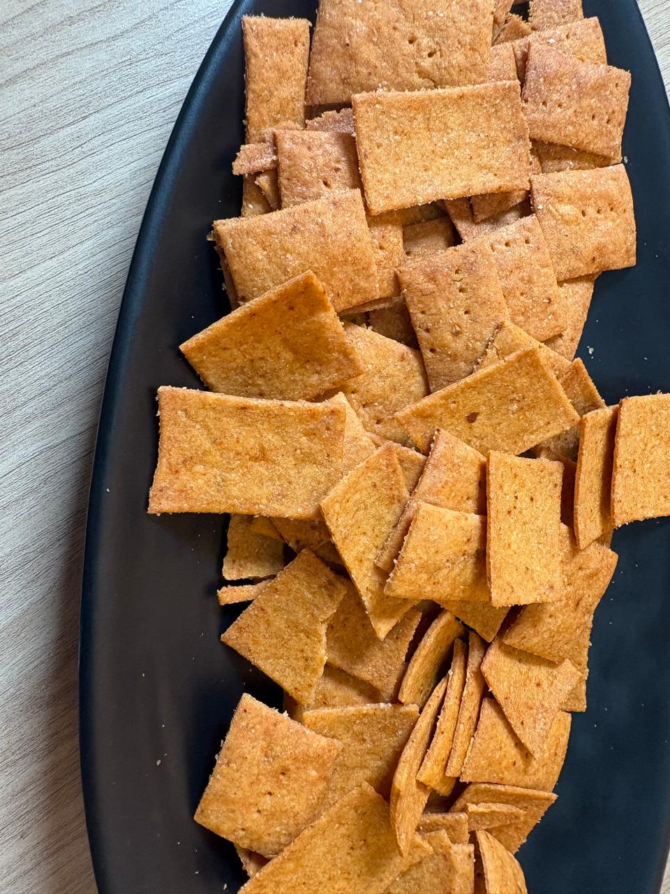 Peri peri whole wheat crackers from Fluffiesta Gurgaon piled on a black oval plate