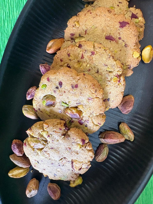 Rose pistachio cookies with pistachios on a black tray