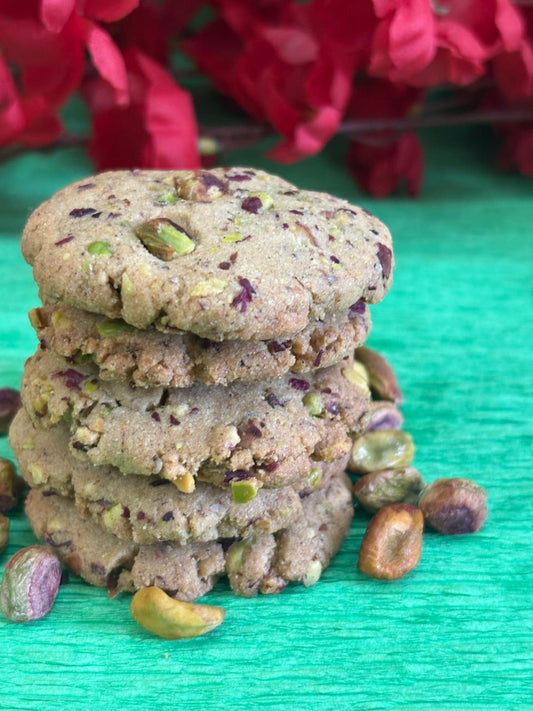 Stack of jowar rose pista cardamom cookies on a green background