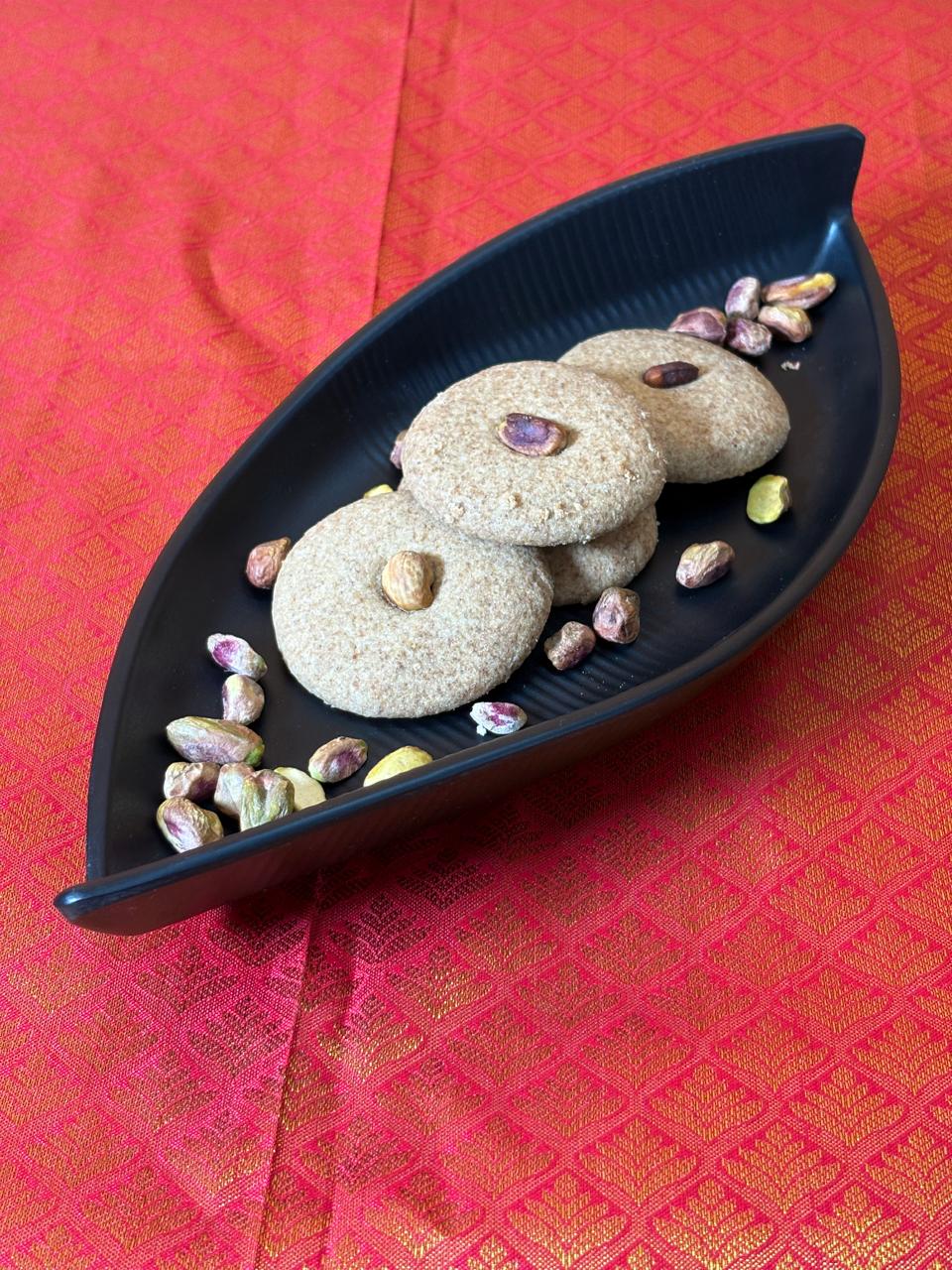 Three jowar nankhatai cookies on a black leaf-shaped tray