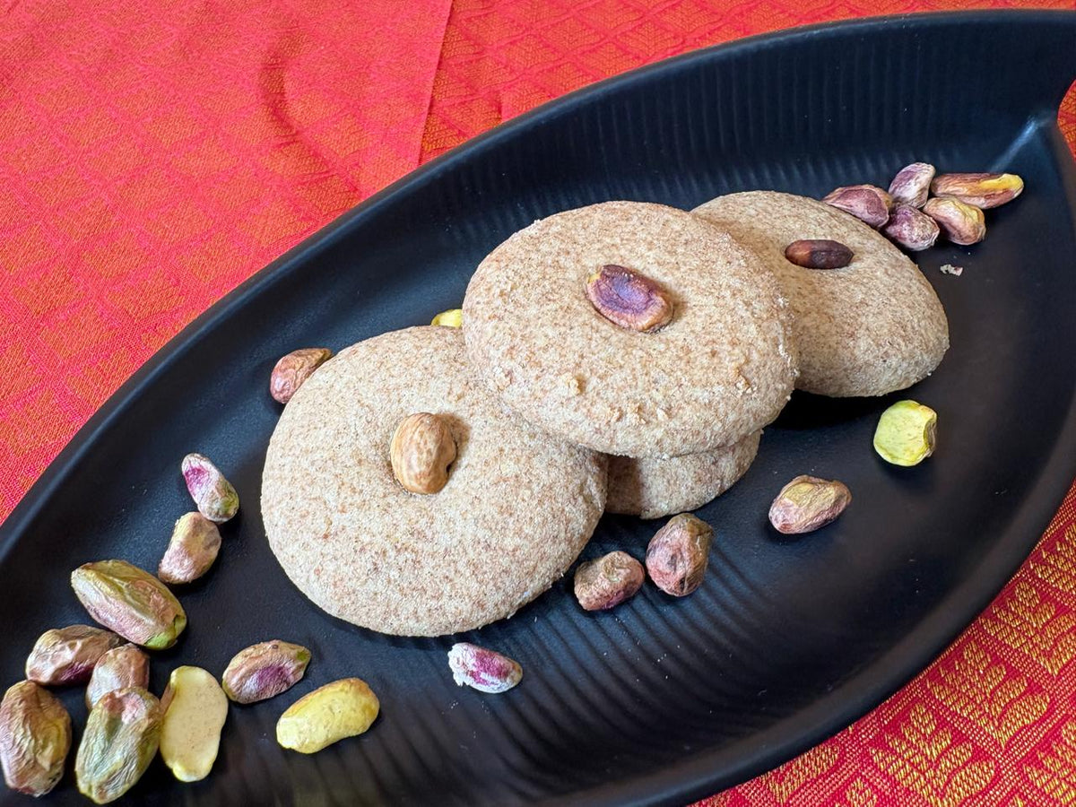 Close-up of jowar nankhatai cookies with pistachio and almond on a black tray