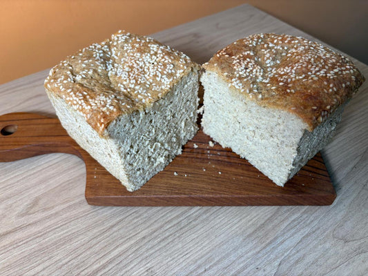 Sliced whole jowar bread loaf with sesame seeds on a wooden board