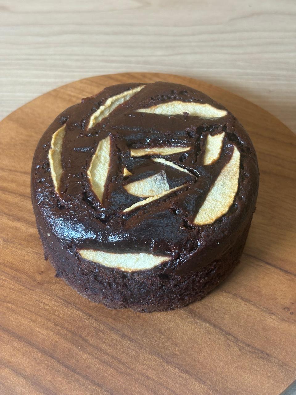 Side view of an dark chocolate apple cake topped with apple slices