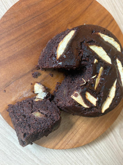 Dark chocolate apple cake with a slice cut out on a wooden board