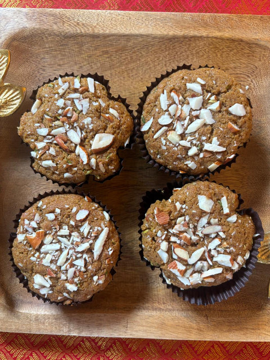 Four malpua muffins with almond flakes on a wooden tray