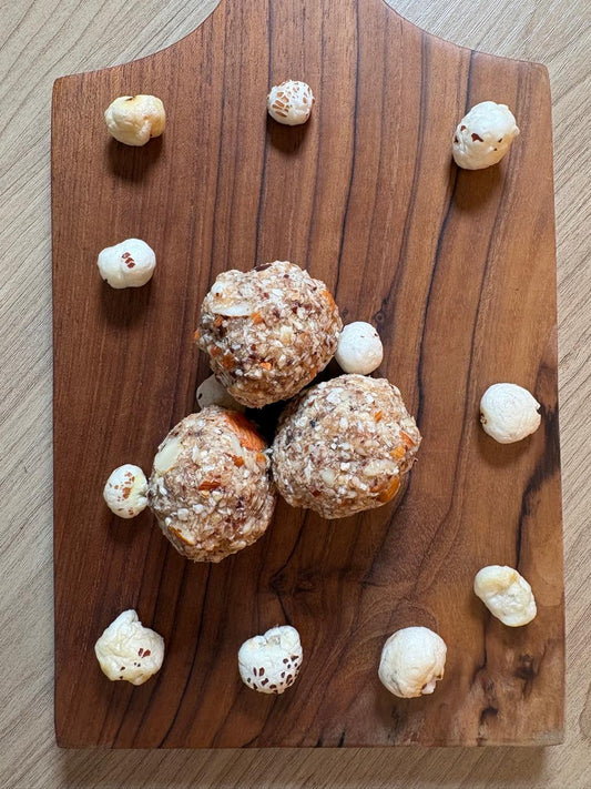Makhana ladoo with dates, almonds and coconut on a wooden board with puffed makhana